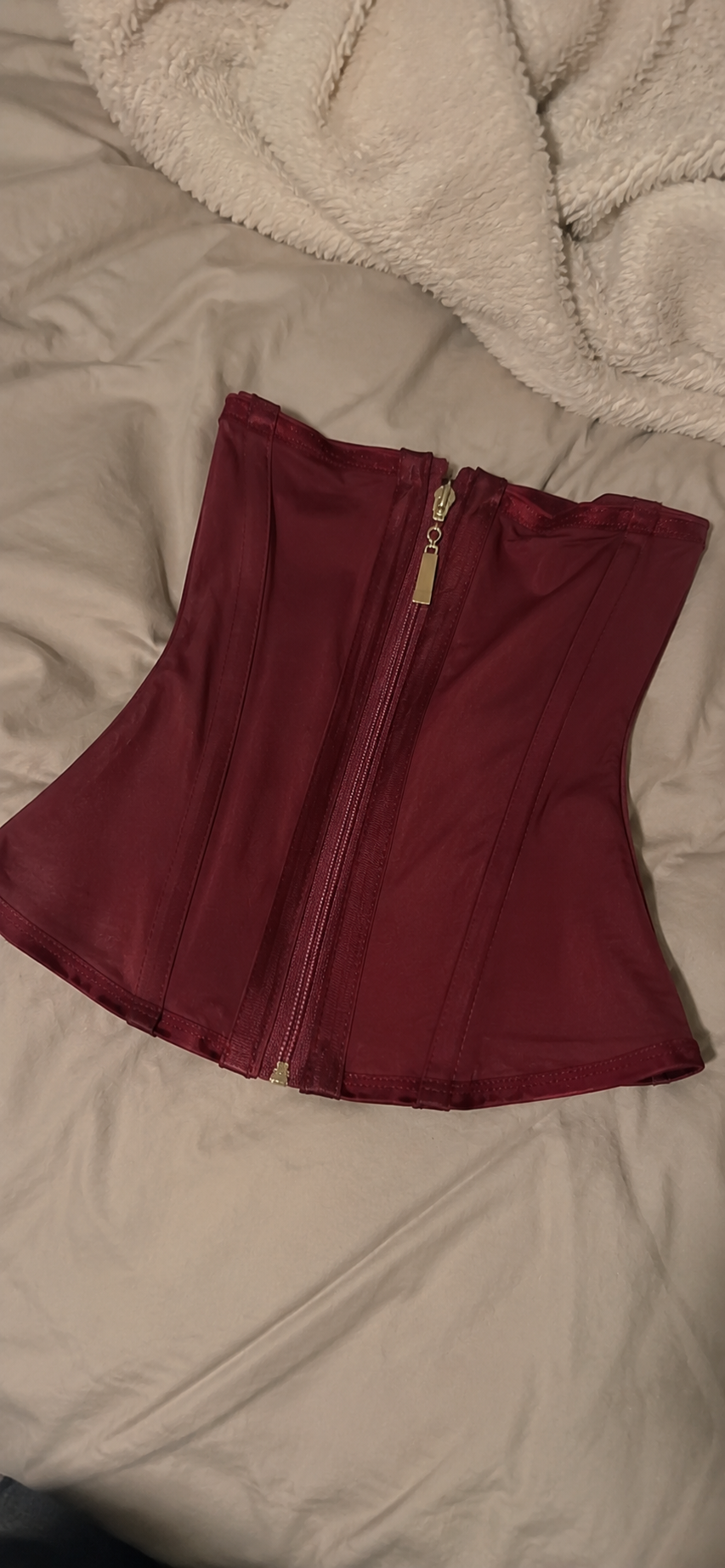 Burgundy corset product-only customer upload on a bed